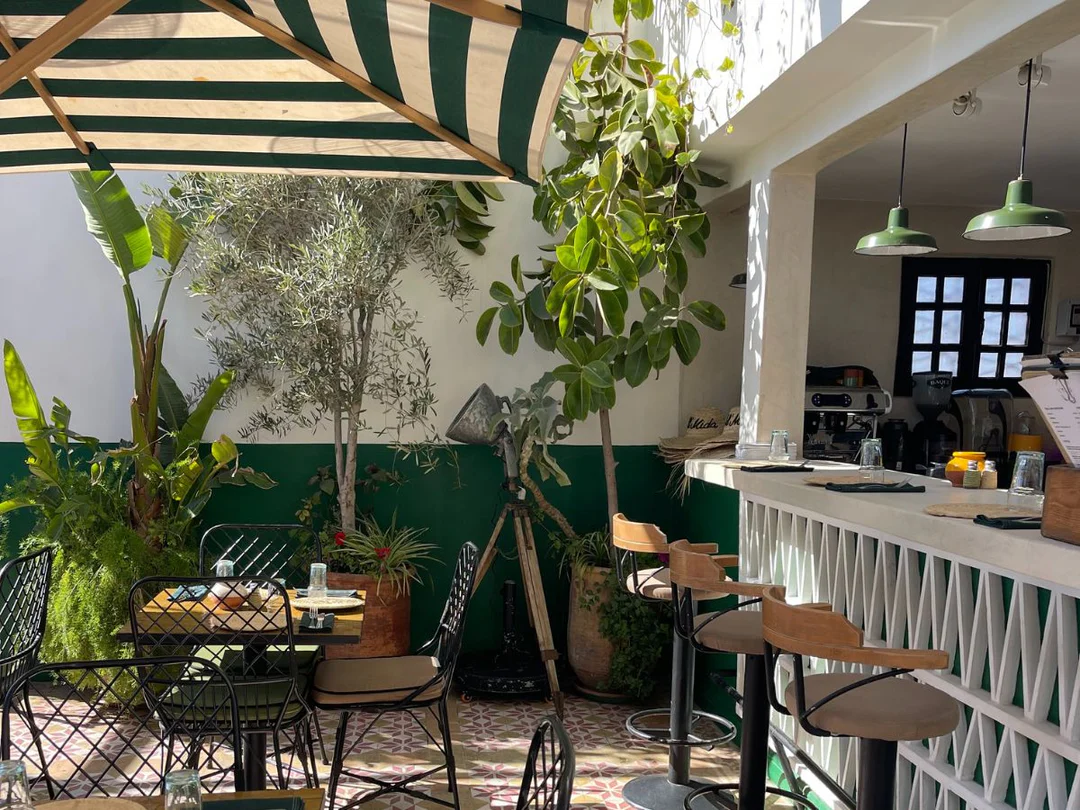 A cozy corner of a Marrakech cafe showing traditional decor, cushions and a cup of coffee on a brass table