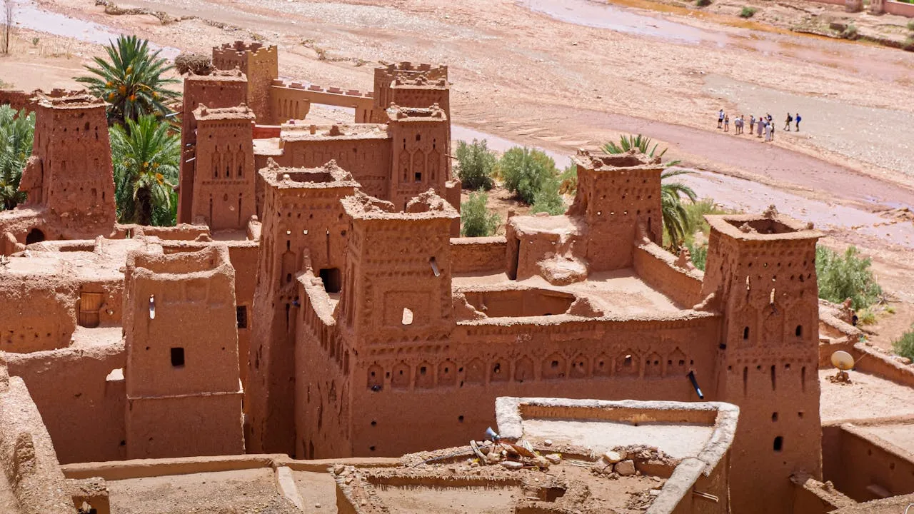 Ancient mud-brick kasbahs of Aït Ben Haddou at sunset, casting long shadows across the UNESCO World Heritage site
