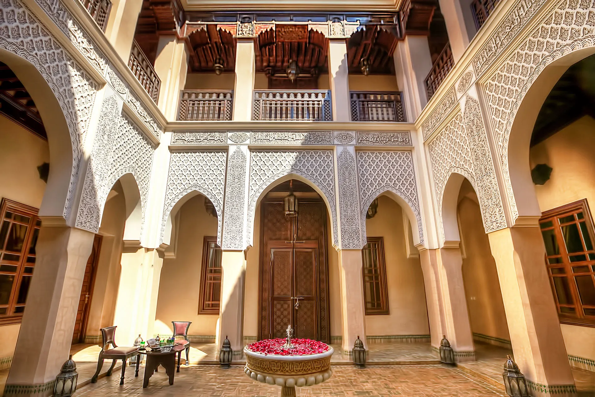 Elegant courtyard dining setup at Riad Kniza with traditional Moroccan lanterns and cushioned seating