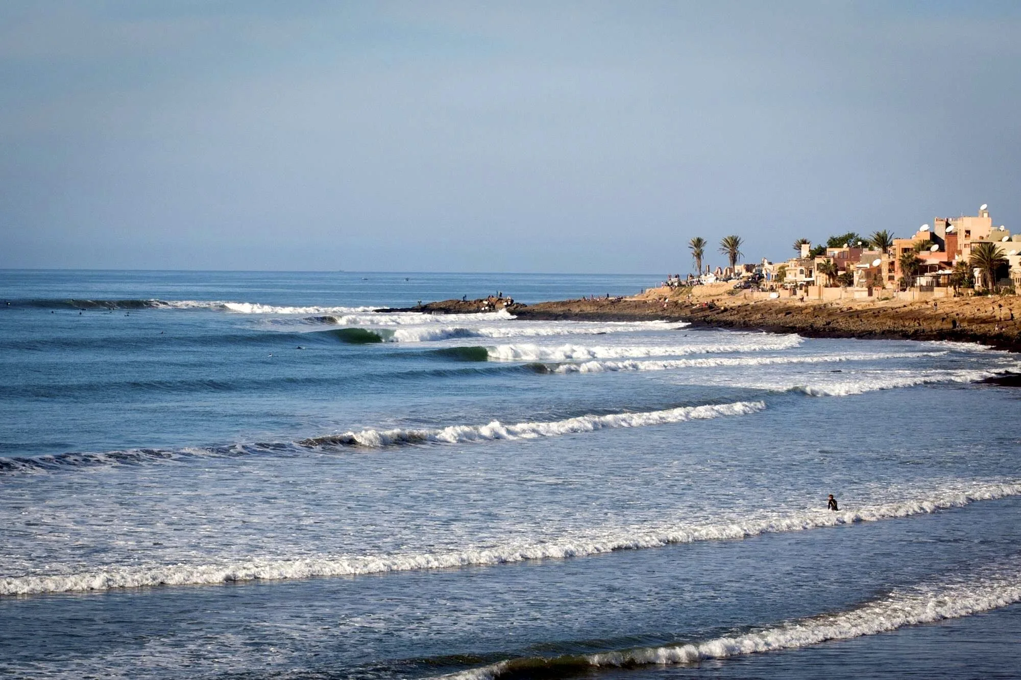 Surfers riding waves at Anchor Point during golden hour in Taghazout