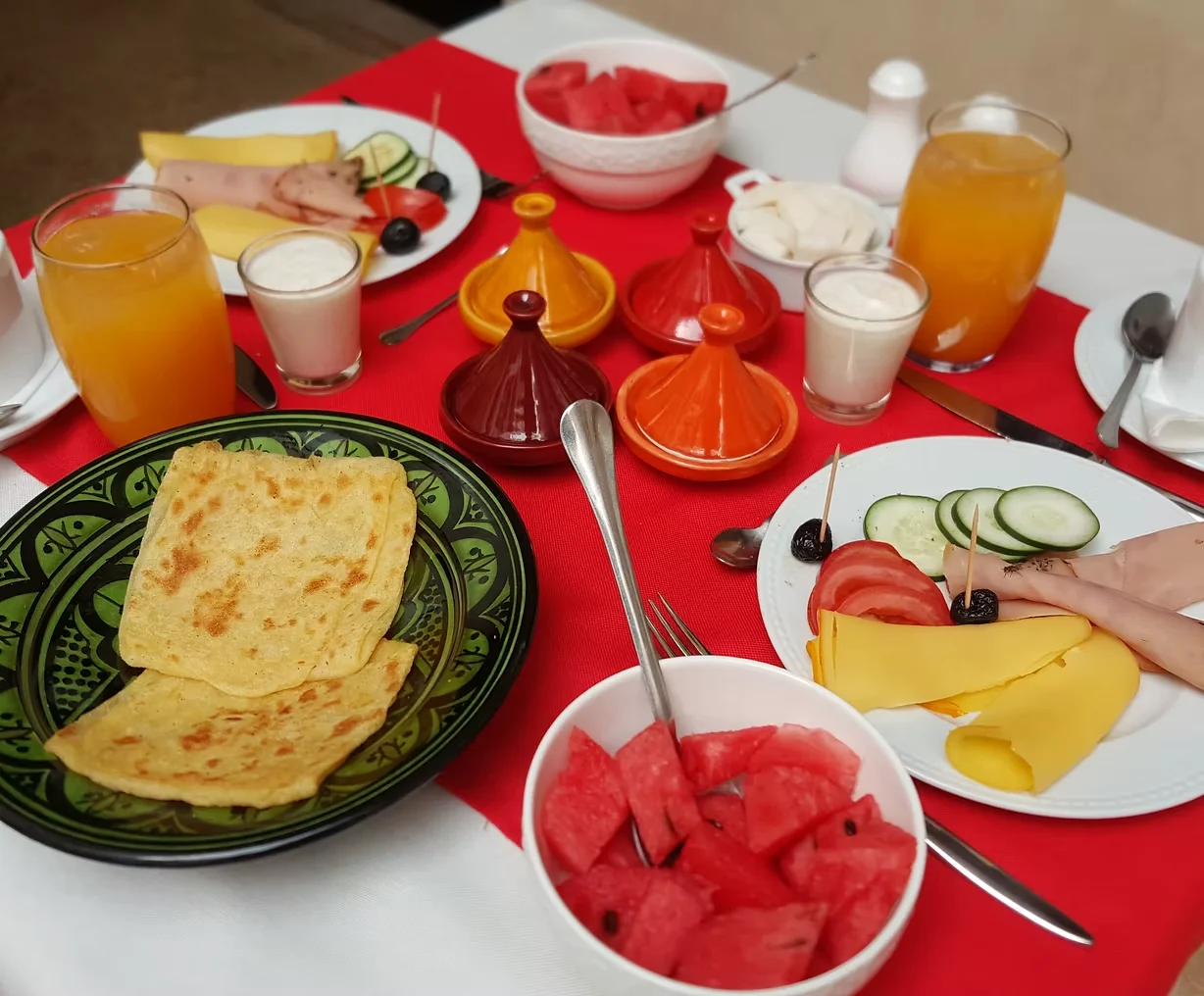 Traditional Moroccan breakfast spread on a riad rooftop with fresh orange juice, pastries, and mint tea